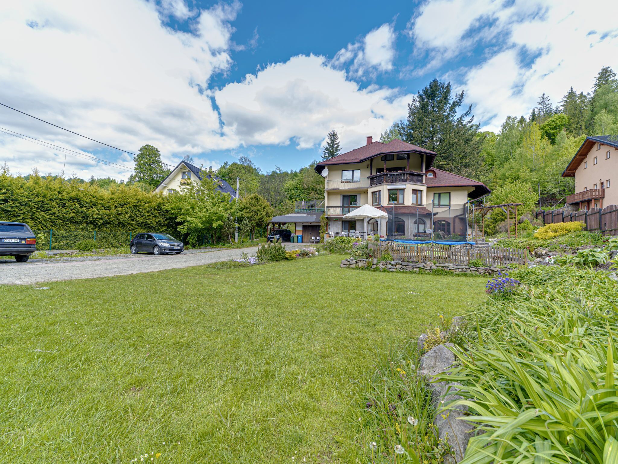 A two-story house with a balcony, a covered outdoor seating area, and a swimming pool.