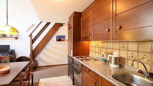 Une cuisine dotée de meubles en bois, d’un plan de travail en granit, d’un évier en acier inoxydable et d’un coin repas avec une table et des chaises.