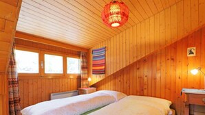 Ein gemütlicher Holzraum mit einem großen Bett, einem Fenster und einer hängenden Laterne.