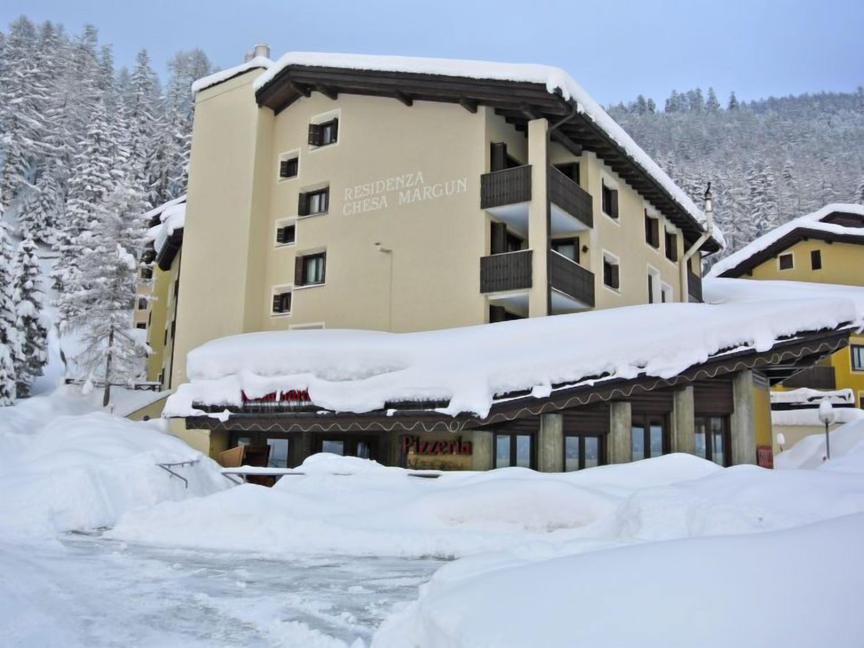 Un hôtel à plusieurs étages, dont le toit et les balcons sont recouverts de neige.