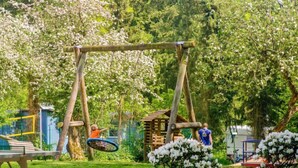 Un parque con un columpio de madera, una mesa de picnic y una pequeña estructura de madera.