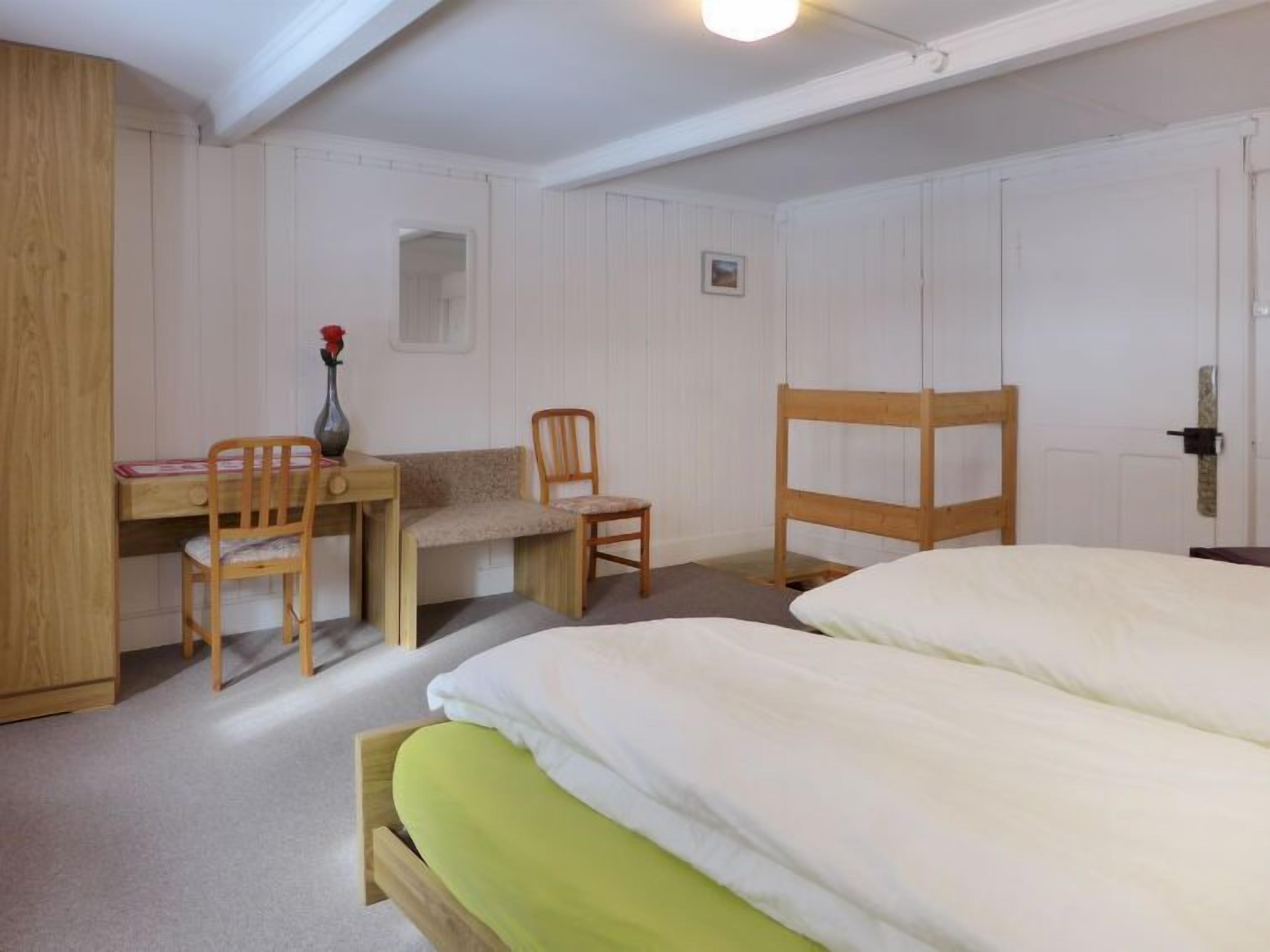 Ein Schlafzimmer mit einem Bett, einem Schreibtisch, zwei Stühlen und einem Kleiderschrank.