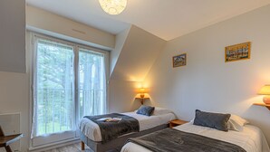 Ein Schlafzimmer mit zwei Betten, einem Fenster mit durchsichtigen Vorhängen und zwei Wandlampen.