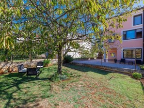Un espace extérieur verdoyant avec un arbre, un banc et un bâtiment doté de grandes fenêtres.