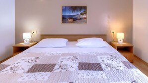Ein Hotelzimmer mit einem großen Bett, zwei Nachttischen mit Lampen, einem Bild an der Wand und einer Steppdecke auf dem Bett.