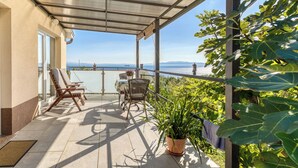 Un balcon abrité avec deux fauteuils, une table et un pot de fleurs.