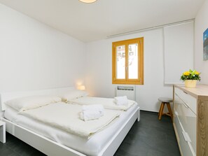 A clean, modern bedroom with a large bed, a desk, and a window. - Residenza Chesa Margun 33-2 by Interhome (Silvaplana-Surlej)