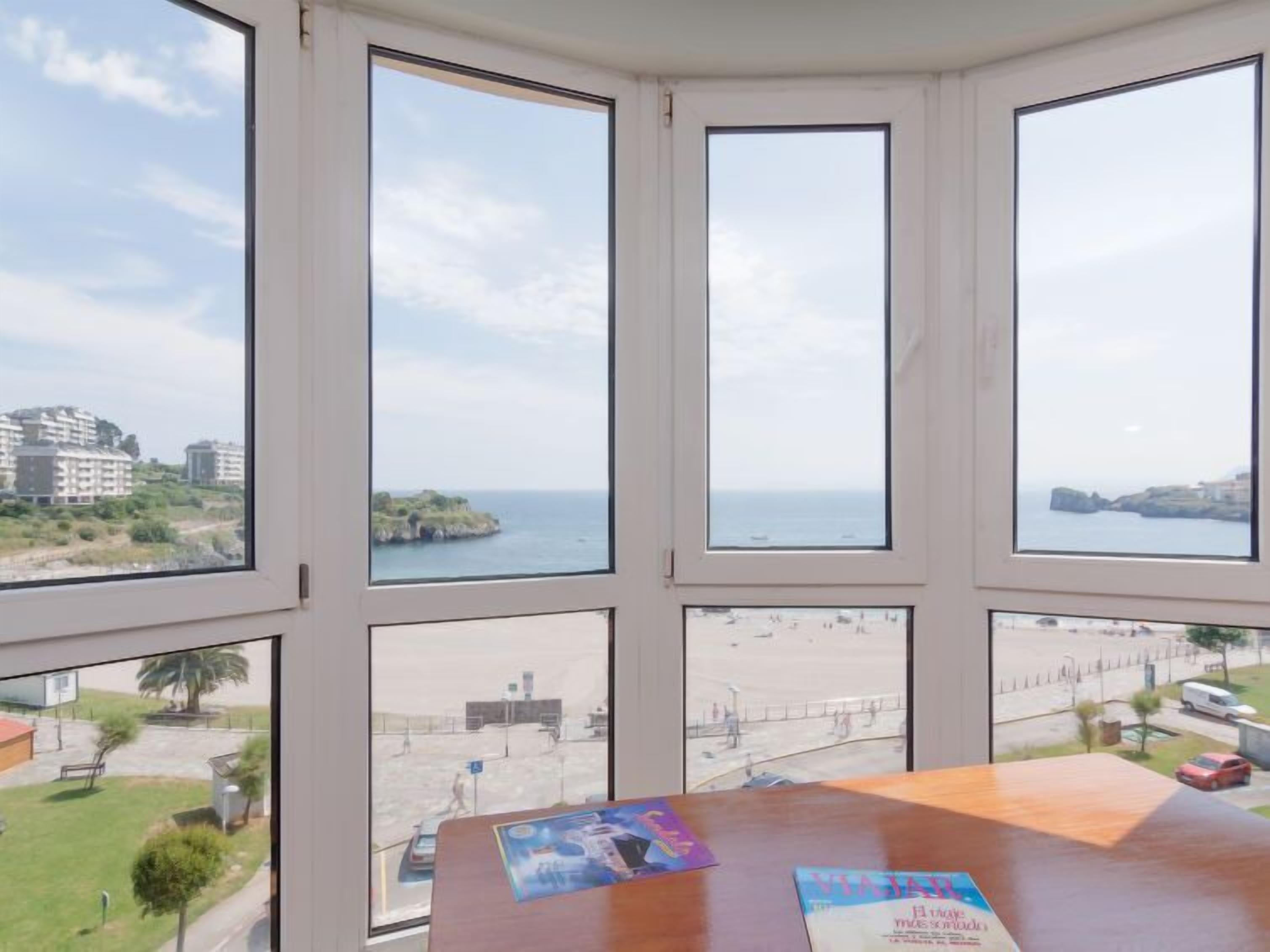 Une pièce dotée d’une grande baie vitrée donnant sur une plage et offrant une vue sur la ville.