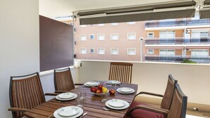 A balcony with a wooden table set for four, surrounded by cushioned chairs. - Marcela by Interhome (St Antoni de Calonge)