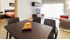 A hotel room with a bed, a TV, a dining table with chairs, a sofa, and a window with curtains. - Marcela by Interhome (St Antoni de Calonge)