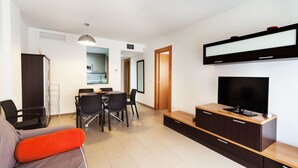 A modern living room with a sofa, TV, and dining area. - Marcela by Interhome (St Antoni de Calonge)