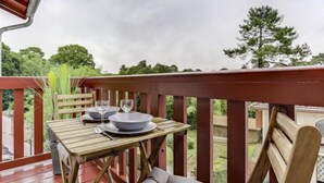 A wooden deck with a table set for two, overlooking a garden. - la Pergola by Interhome (Hossegor)