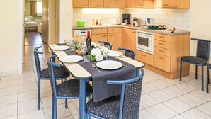 Una cucina moderna con mobili in legno, forno integrato e zona pranzo con tavolo apparecchiato per quattro persone.