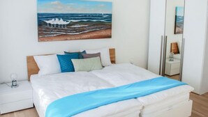 A bedroom with a bed, a nightstand, a bedside lamp, a wardrobe, and a painting of the ocean. - LaVille B-2-3 by Interhome (Locarno)