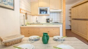 A compact kitchen with white cabinets, a wooden countertop, and a small island. There is a sink, a stove, and a microwave above the island. - Le Prariond (Val Claret) by Interhome (Tignes)