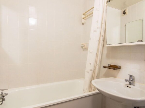 A bathroom with a bathtub, a sink, and a mirror. - Le Prariond (Val Claret) by Interhome (Tignes)