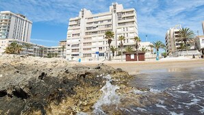 A beachfront hotel with multiple floors, balconies, and palm trees. - Les Roquetes by Interhome (Calpe/Calp)