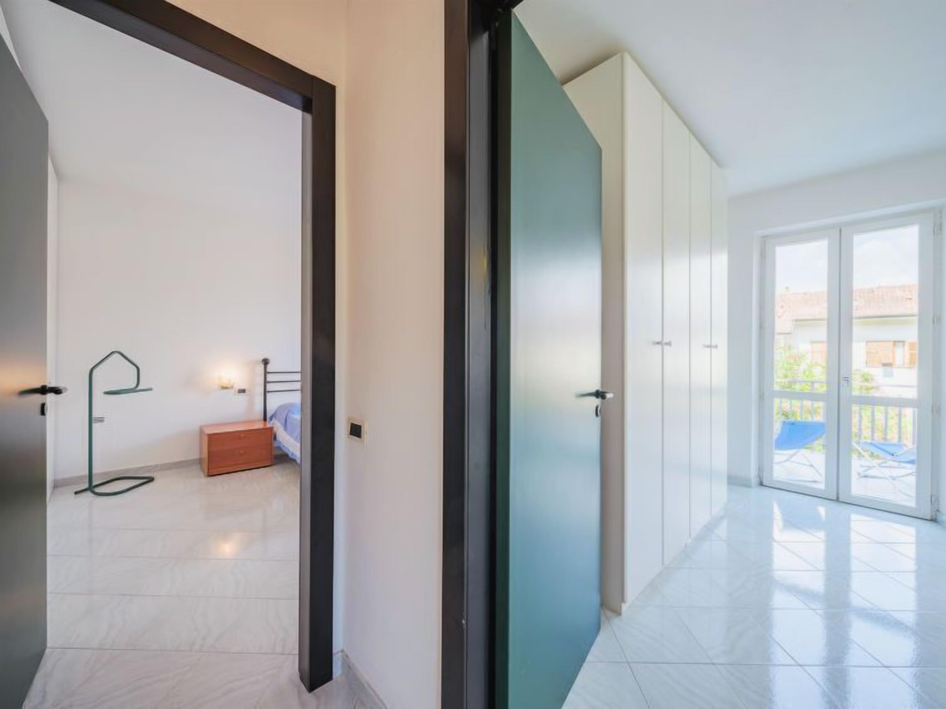 A modern apartment with a spacious living area, a bedroom with a bed and dresser, and a balcony with a view.