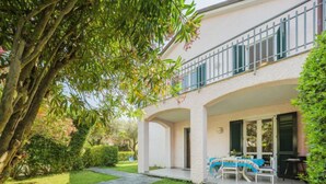 A two-story house with a covered patio area, a stone pathway, and a small table with a blue tablecloth. - Lucerna Due by Interhome (Ameglia)