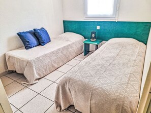 A room with two beds, a small table, and a window.