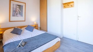 A bedroom with a bed, a nightstand, a framed picture, a wooden wardrobe, and a door. - Roche Blanche 183 by Interhome (Val Thorens)