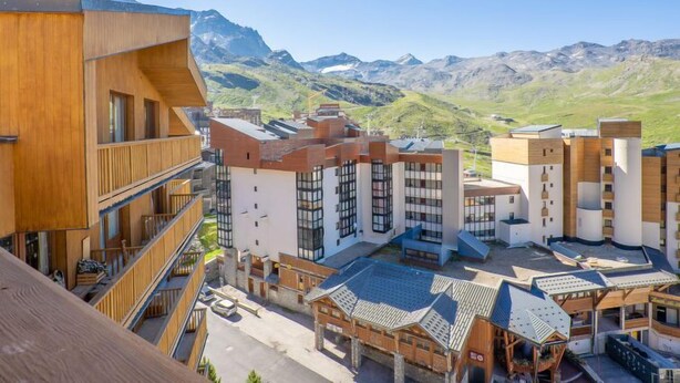 A modern building complex with multiple floors, large windows, and a view of mountains in the background. - Roche Blanche 183 by Interhome (Val Thorens)