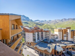 A modern building complex with multiple floors, large windows, and a view of mountains in the background.