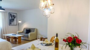 Ett hotellrum med en matplats, en soffa, ett bord dukat för två personer och en vas med röda rosor.