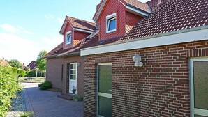 Ett tvåvåningshus byggt av tegel med ett rött tegeltak, en ytterdörr och ett litet fönster.