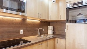 Een moderne keuken met houten kastjes, een roestvrijstalen magnetron, een ingebouwde oven en een koffiezetapparaat.