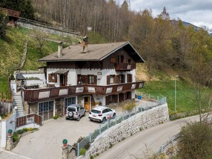 A two-story chalet with a balcony, a stone wall, and a paved driveway. - Santa Lucia by Interhome (Bormio)