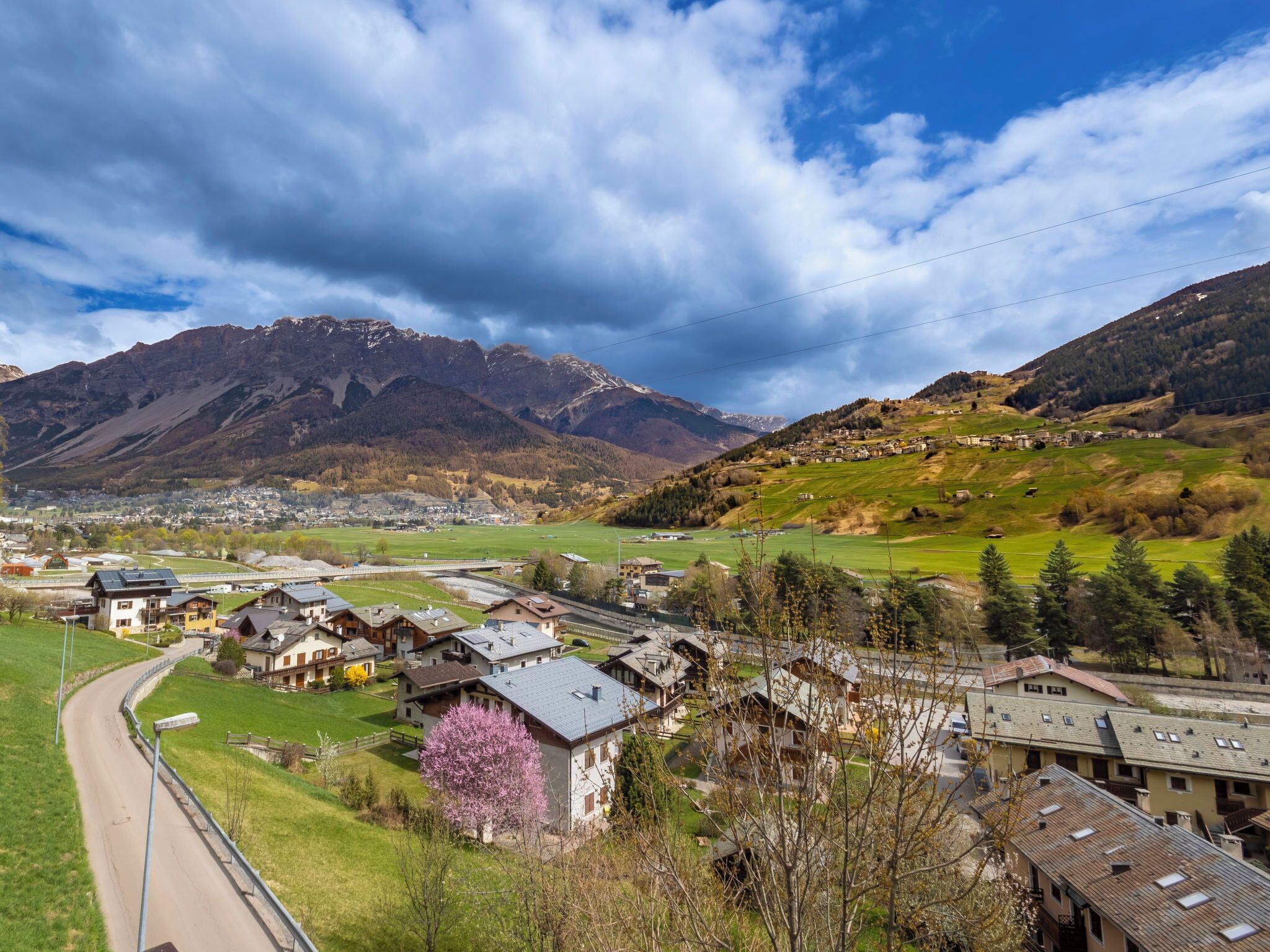 A mountainous landscape with a village, houses, and a road.