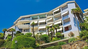 Un hotel de diversos pisos amb balcons, envoltat de vegetació exuberant i palmeres.