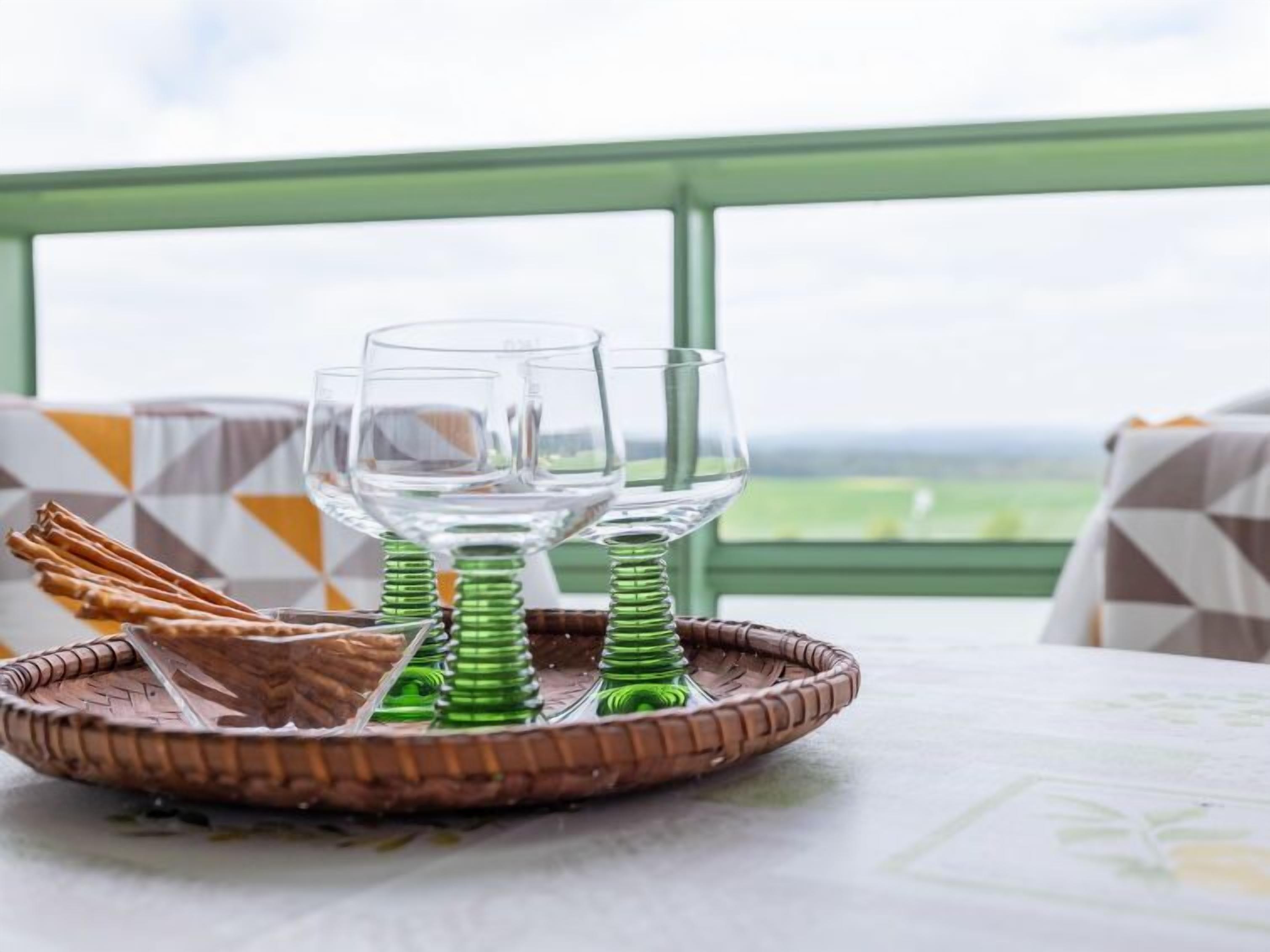 Una mesa de comedor con una bandeja de mimbre que contiene dos copas de vino y palitos de pretzels.