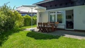 Une maison avec un patio, une table et des chaises.