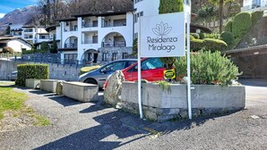A sign for 'Residenza Miralago' with a view of a building and a parked car. - Residenza Miralago Apt. B16 by Interhome (Piazzogna)