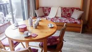 Una habitación acogedora con una mesa de madera preparada para el té, un sofá estampado y vistas a través de un amplio ventanal.