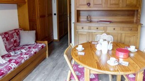 Una habitación acogedora con un sofá de madera, una mesa de comedor con sillas y armarios de madera.