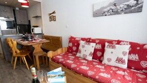 Zona d'estar acollidora amb un sofà vermell, mobles de fusta i una petita taula de menjador.