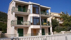 Un immeuble à plusieurs étages doté de balcons, d’une clôture blanche et surplombant un ciel bleu azur.