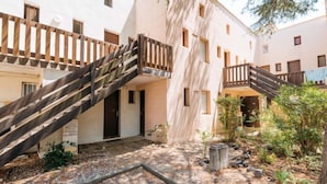 A courtyard with a wooden staircase leading to a building with multiple windows and balconies. - Résidence Green Village 2 by Interhome (Cap d'Agde)