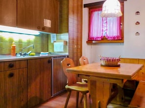A compact kitchen with wooden cabinets, a sink, and a dining area with a table and chairs.