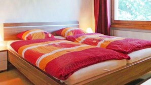 Un lit double avec un cadre en bois et une couverture colorée.