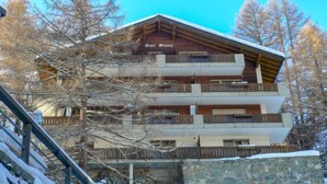 Un immeuble à plusieurs étages, doté de balcons, d’un rez-de-chaussée en pierre et d’une structure supérieure en bois.