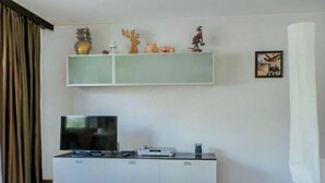 Un salon moderne avec un téléviseur à écran plat, un meuble de rangement blanc et un tableau encadré au mur.