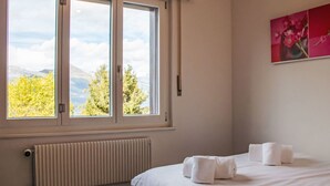 Ein Hotelzimmer mit großem Fenster, Heizkörper, einem Bett mit weißer Bettwäsche und einem Bild an der Wand.