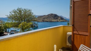 Un balcon avec un mur jaune, une porte en bois et un appareil de climatisation.