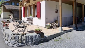 A traditional chalet with a stone foundation, red shutters, and a patio with outdoor furniture. - Apartment Rösli by Interhome (Lauterbrunnen)