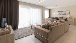 Un soggiorno moderno con un divano, una TV e un'area pranzo con sedie e un tavolo.