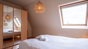 Una camera da letto con un letto, un armadio, una lampada a sospensione e una finestra.